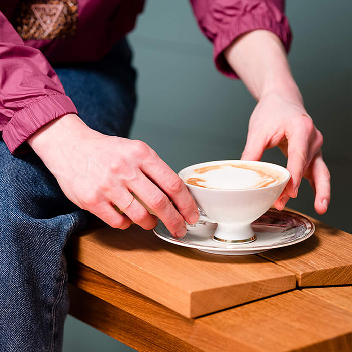 Eine Frau hält eine Tasse mit frischem Kaffee im Barbereich von Ruths Berlin
